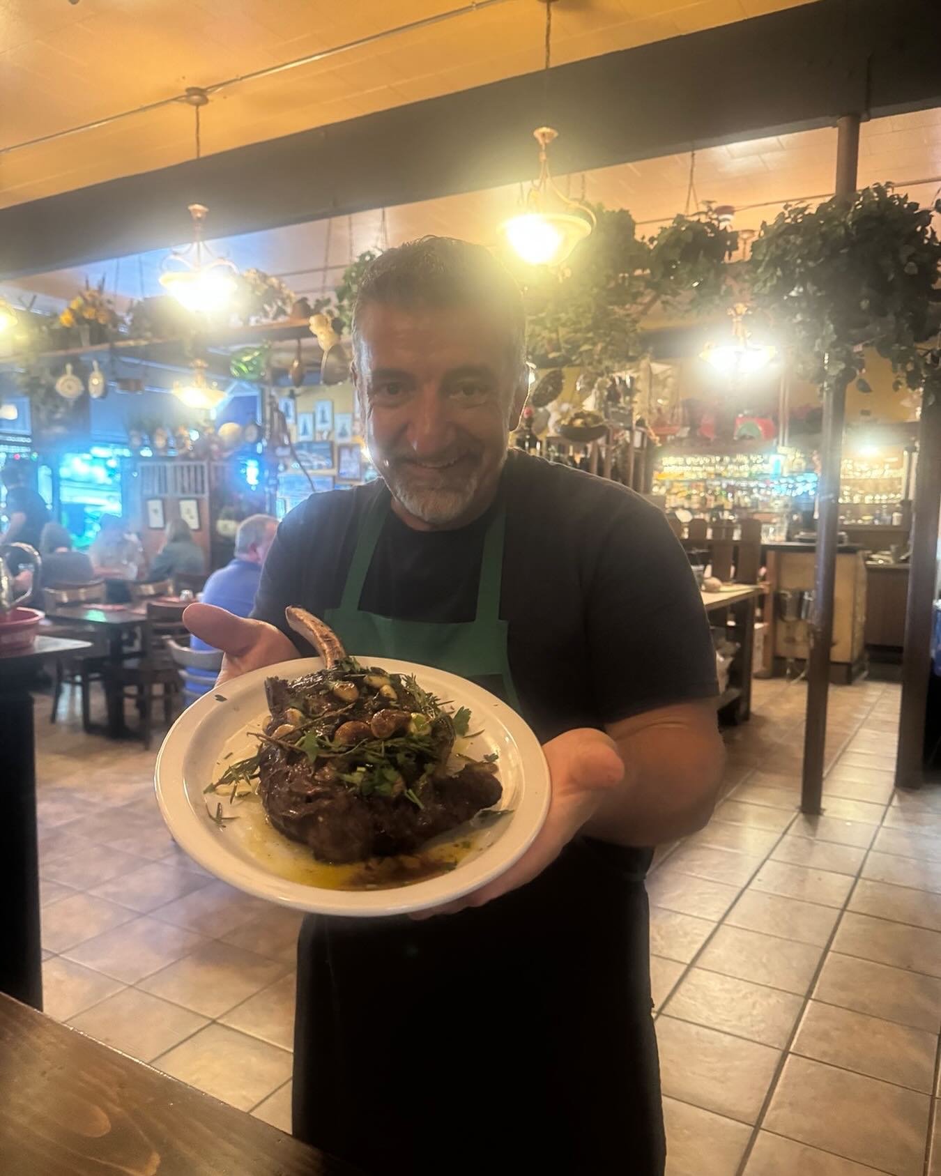 Chef Michele holding a plated dish in the dining room at Il Lucano