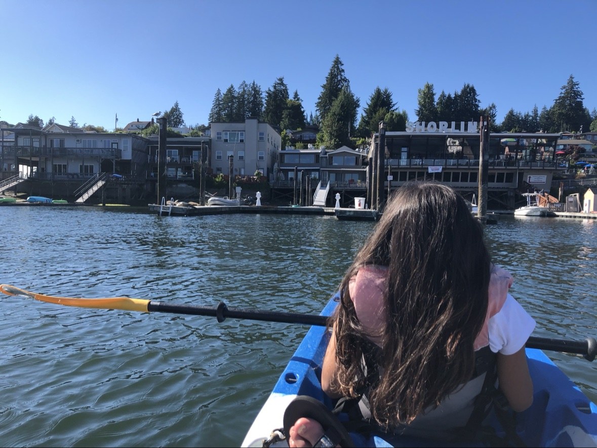 View from a kayak in Gig Harbor, paddling toward the waterfront buildings on a clear day
