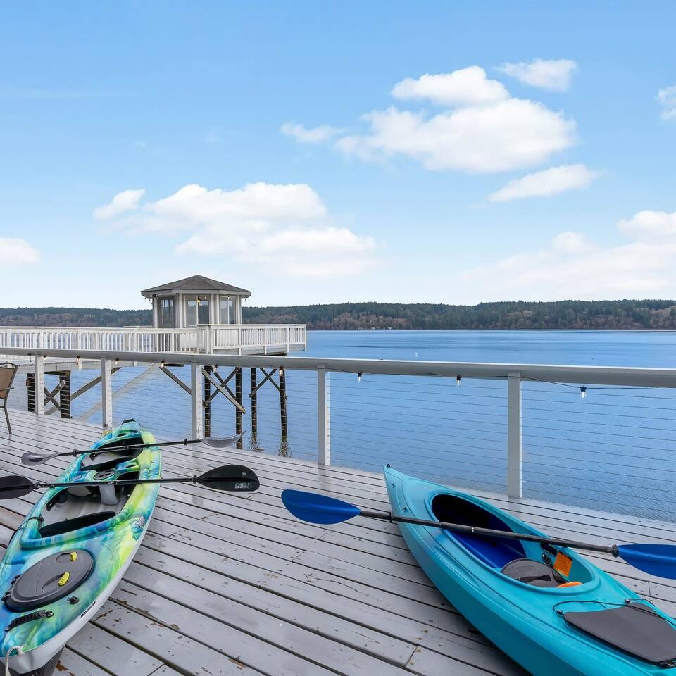 Two kayaks with paddles on the waterfront deck, dock gazebo and Olalla Bay behind